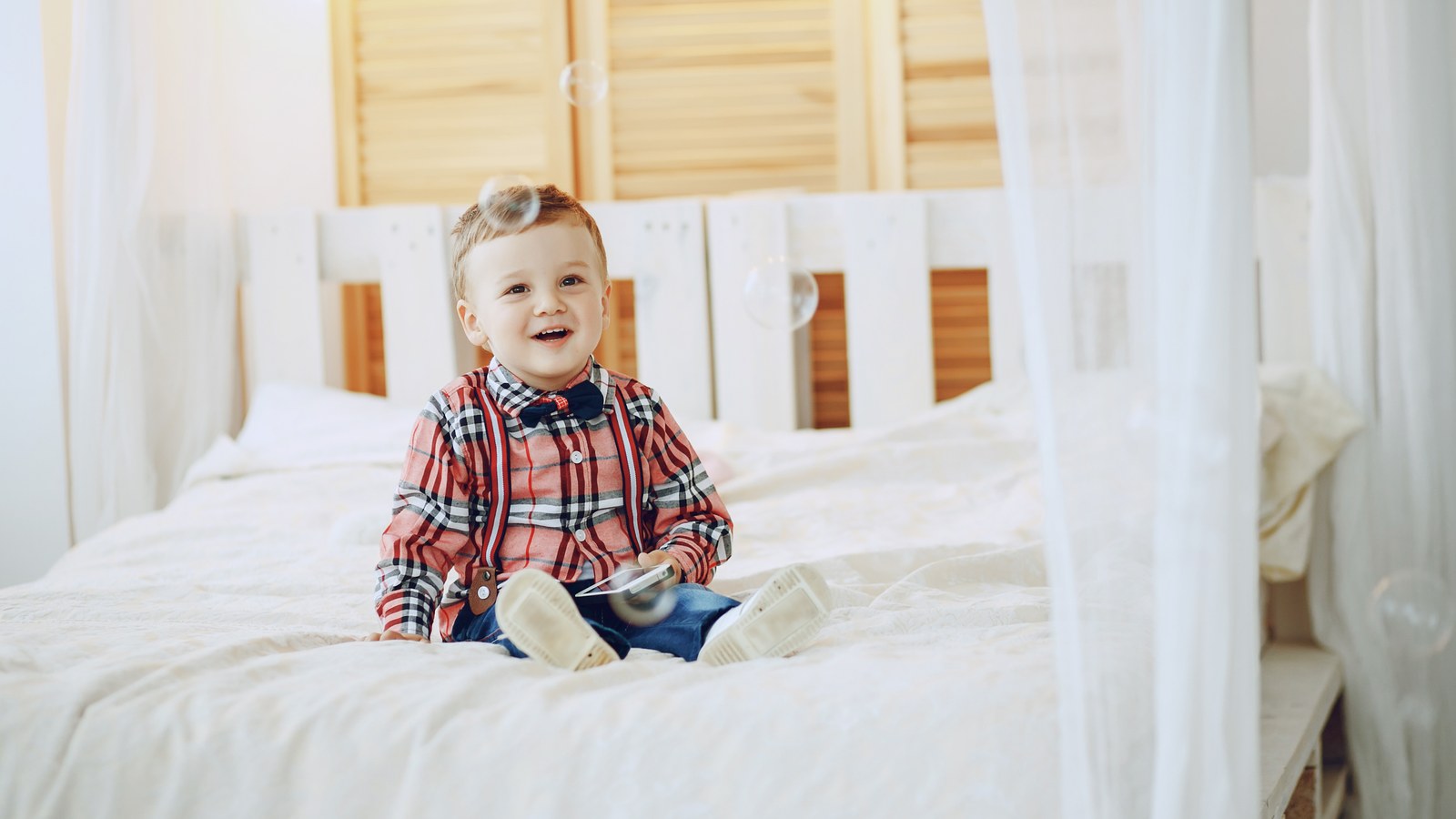 Bébé d'un an joyeux debout dans son lit en bois souriant