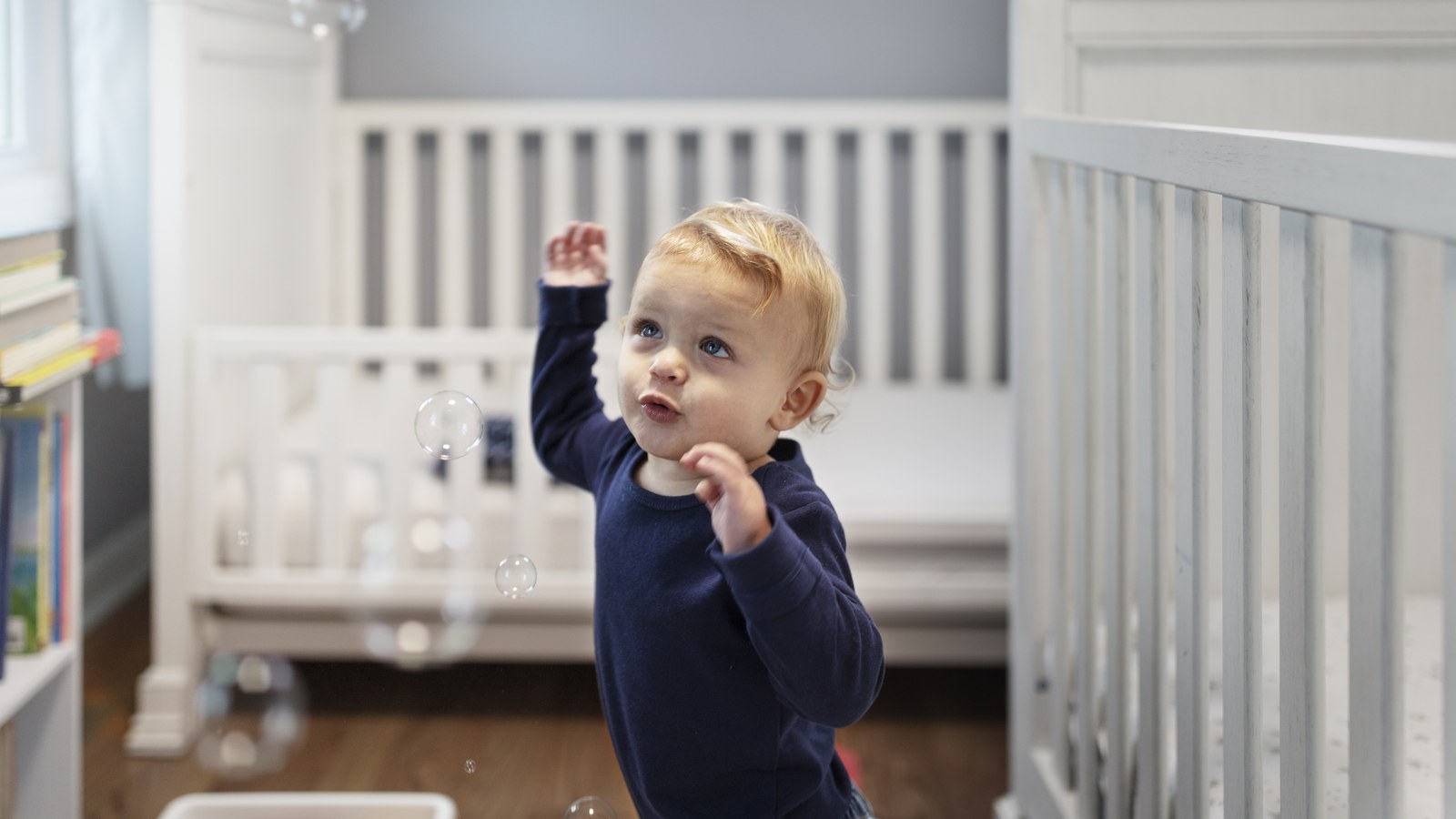 Un bambin de 2 ans debout dans son lit à barreaux protestant contre le coucher