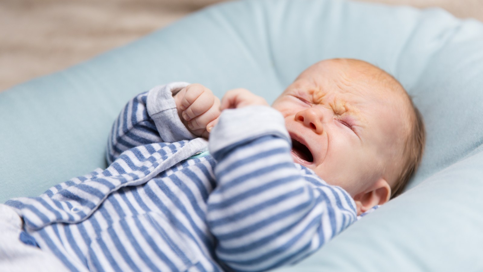 Crying infant being comforted by loving parent in a safe nursery setting