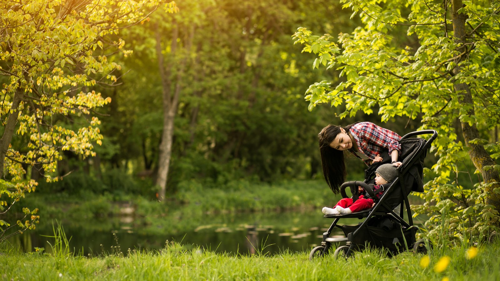 Mère promenant son bébé confortablement installé dans une poussette sous surveillance au parc