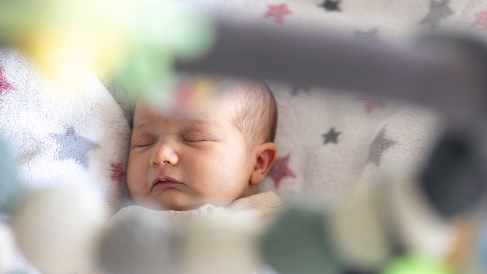 Infant peacefully sleeping in a safe crib next to a baby sleep schedule chart