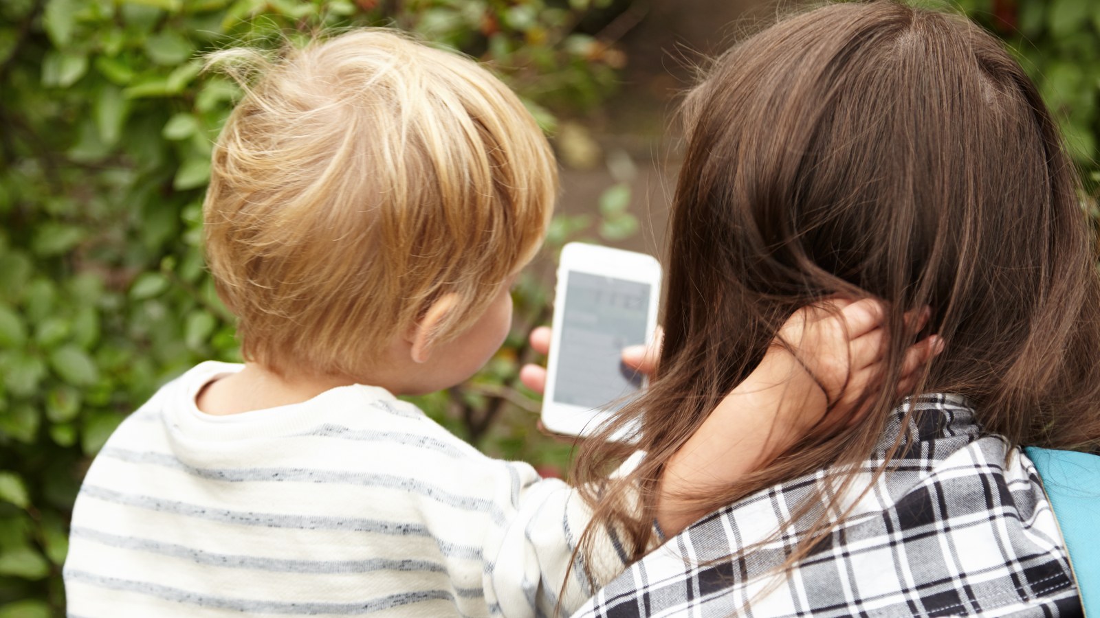 Un parent regardant un smartphone avec un enfant
