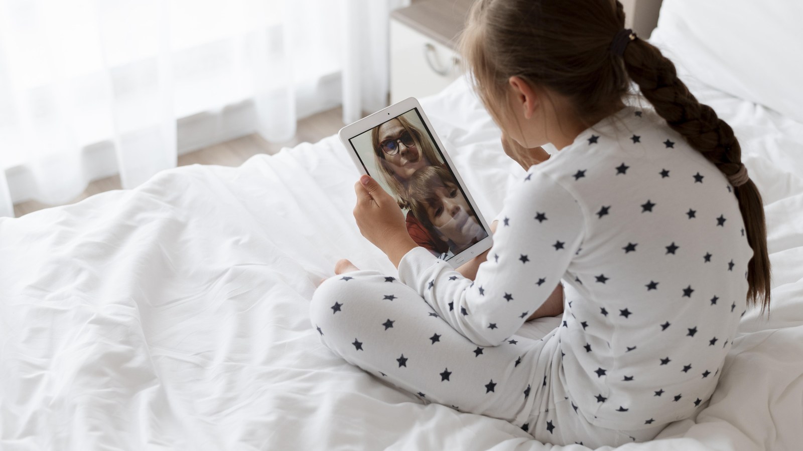 An iPad resting on a wooden nursery shelf displaying a baby monitor video feed overlooking a clean, safe Scandinavian crib.