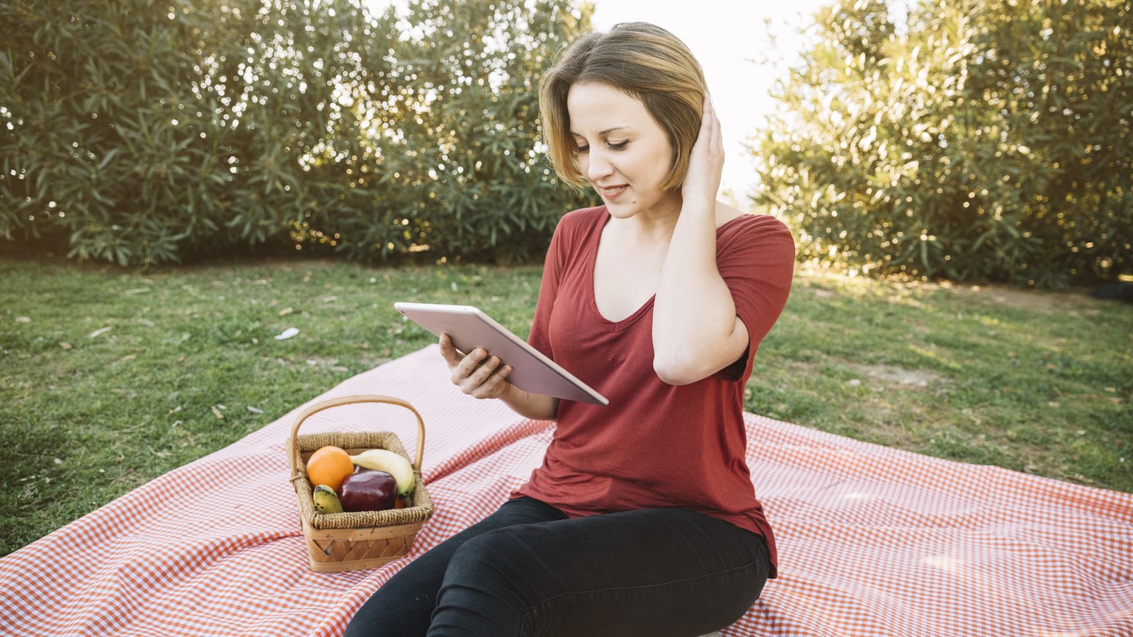 A relaxed mother sitting on her outdoor backyard patio garden holding her smartphone while keeping a watchful eye on her sleeping infant.