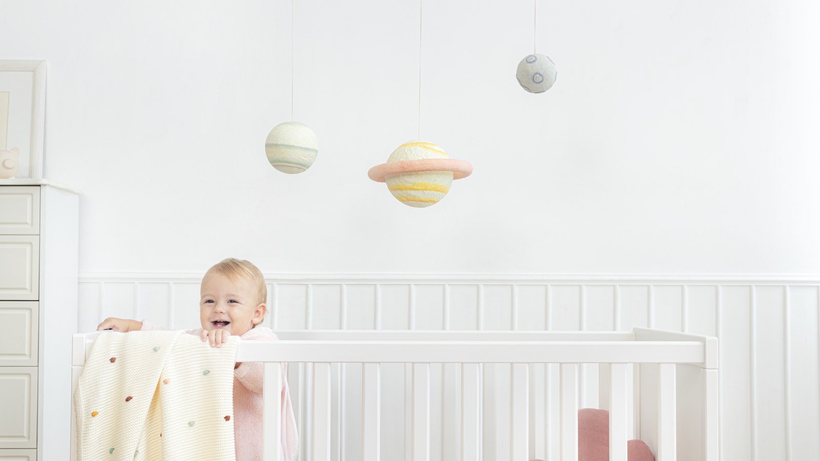 A comparison setting in a bright modern nursery with a phone baby monitor and an unplugged smart camera hardware device.