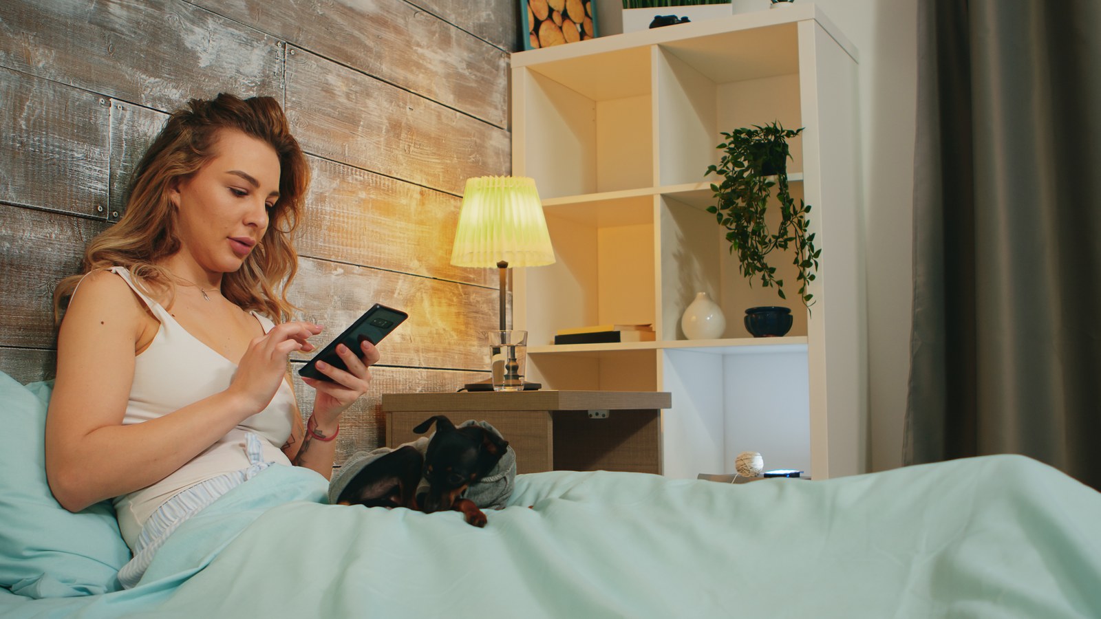 A smartphone resting securely on a nightstand connected to a safe charger while monitoring a baby sleeping peacefully nearby.