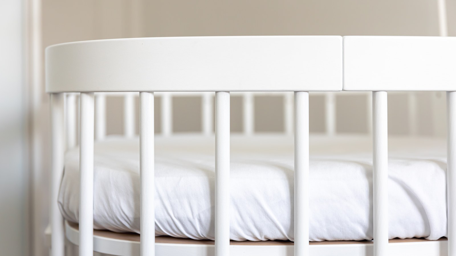 Clean white baby bed and firm mattress waiting for newborn meeting AAP safe sleep guidelines