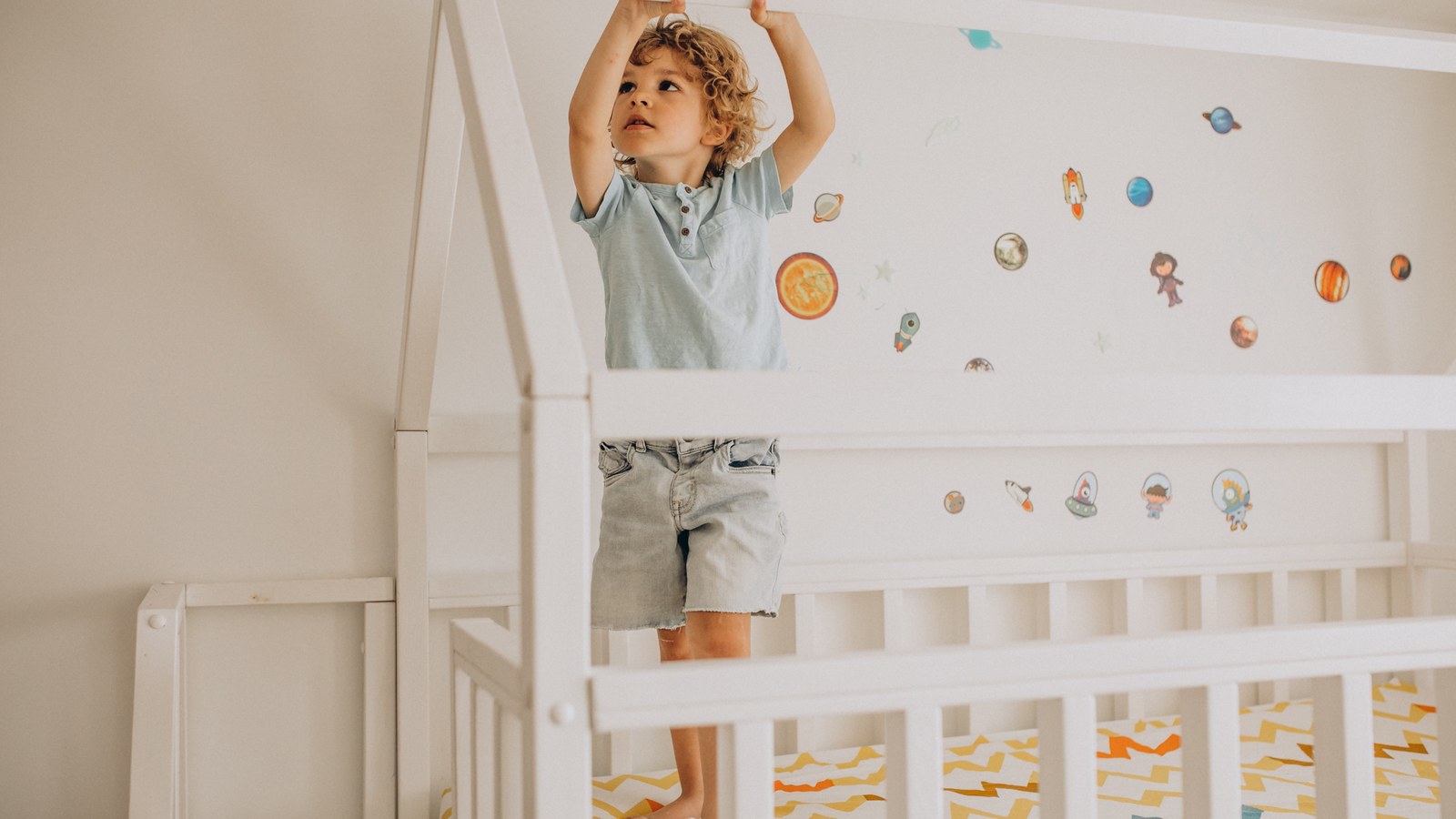Bambino piccolo con il piedino sulla sponda del lettino nel tentativo di scavalcare